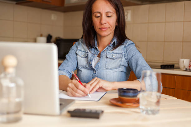 istock Woman writing in notebook in the kitchen. 1284052767