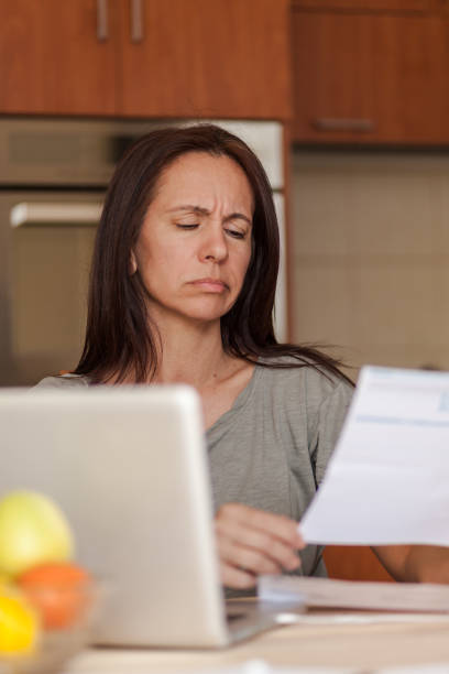 istock Mid adult woman reading her problematic home finances. 1284052824