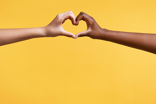 Diverse hands with love sign on yellow background