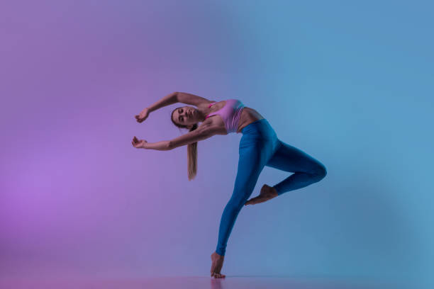 istock Young sportive woman training isolated on gradient studio background in neon light. athletic and graceful 1284053106