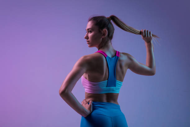 joven entrenamiento de mujer deportiva aislada sobre fondo de estudio degradado en luz de neón. atlético y elegante - modelo de artista fotografías e imágenes de stock