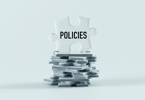 Stack of jigsaw puzzle pieces, white background. Policies.