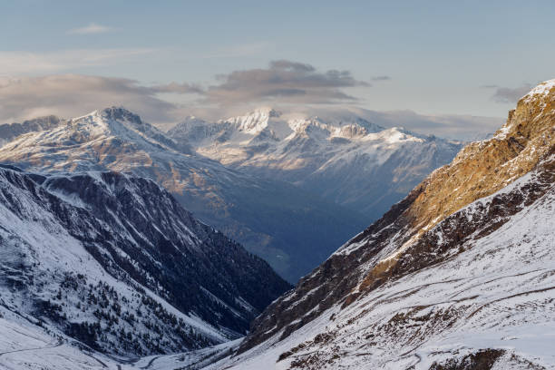 Alpen mountain valley with building and snow covered peaks under cloudy sky