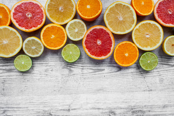 istock Halved citrus fruits arranged as a border on a light wooden surface, viewed directly above with copy space 1284055669
