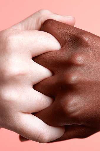 Diverse hands clasped on pink background