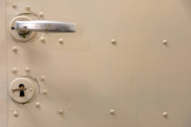 istock Old white metal door with lock, key and heck or door handle 1284056346
