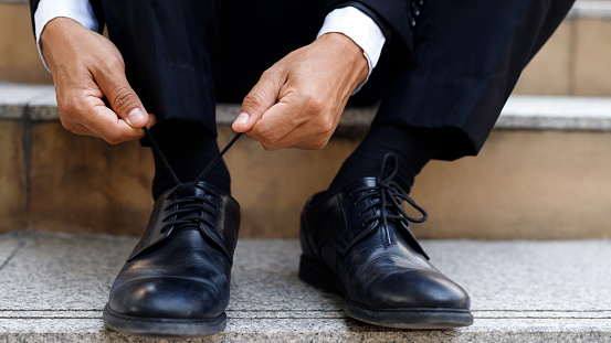 Business men tie shoelaces at office