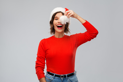 christmas, holidays and people concept - happy smiling young woman in santa helper hat over grey background
