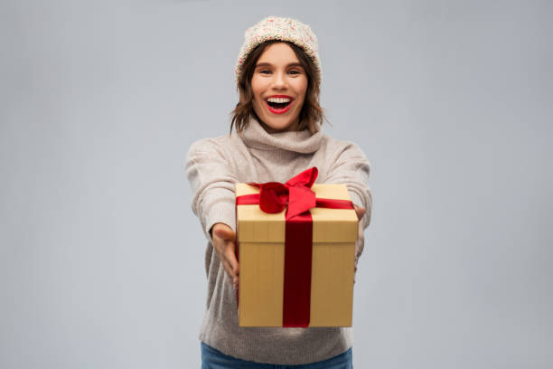 istock young woman in knitted winter hat holding gift box 1284058846