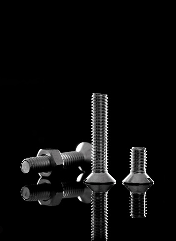 Metal bolts and nuts on black background