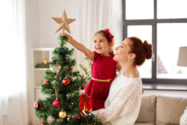gelukkige familie die kerstboom thuis verfraait - christmas people stockfoto's en -beelden