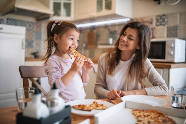 Mother and daughter eating pizza at home.