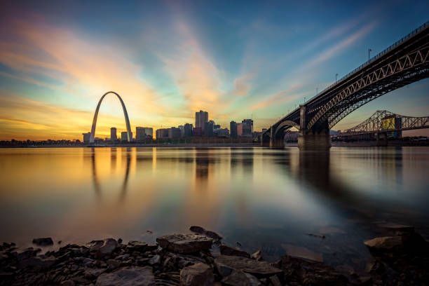 St. Louis City Skyline St. Louis skyline at sunset including the Gateway Arch and Eads Bridge reflected in the Mississippi River. jefferson national expansion memorial park stock pictures, royalty-free photos & images