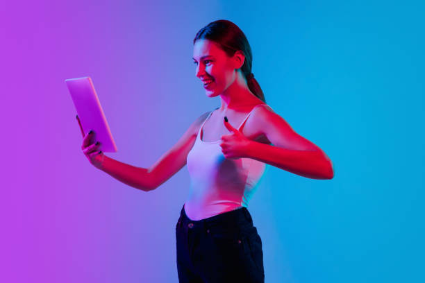 istock Young caucasian woman's portrait on gradient blue-purple studio background in neon light 1284065098