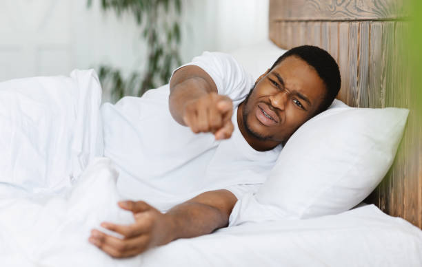 istock Disturbed Sleepy Man Pointing Finger At Camera Lying In Bedroom 1284065376