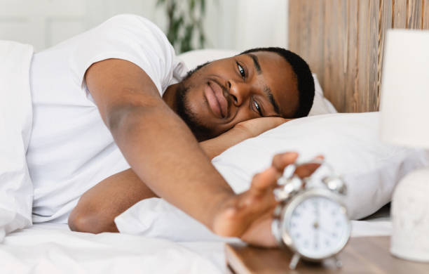 istock Wellslept Black Man Turning Off Alarm-Clock Waking Up In Bedroom 1284066310