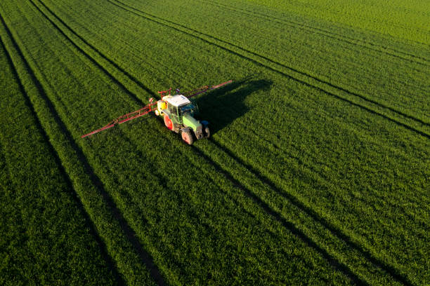 Agricultural tractor spraying field Aerial view of a tractor spraying green field with pesticide, insecticide, herbicide chemicals in sunlight. overcasting stock pictures, royalty-free photos & images