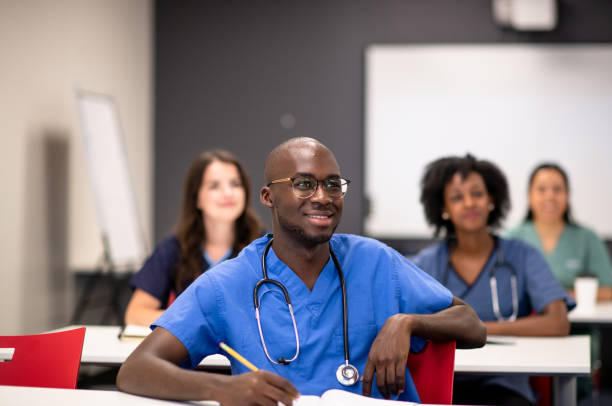 Taking courses in medical school A diverse group of students dressed in medical wear learn in a classroom setting. medical student photos stock pictures, royalty-free photos & images