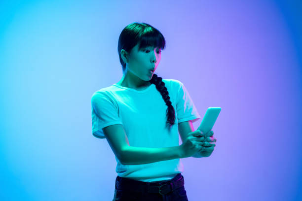 istock Young asian woman's portrait on gradient blue-purple studio background in neon light 1284071051