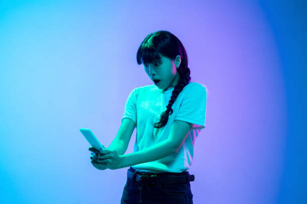 istock Young asian woman's portrait on gradient blue-purple studio background in neon light 1284071053
