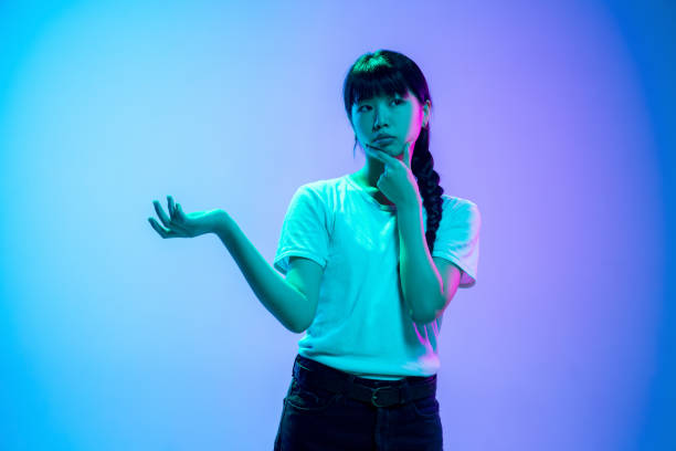 istock Young asian woman's portrait on gradient blue-purple studio background in neon light 1284071055