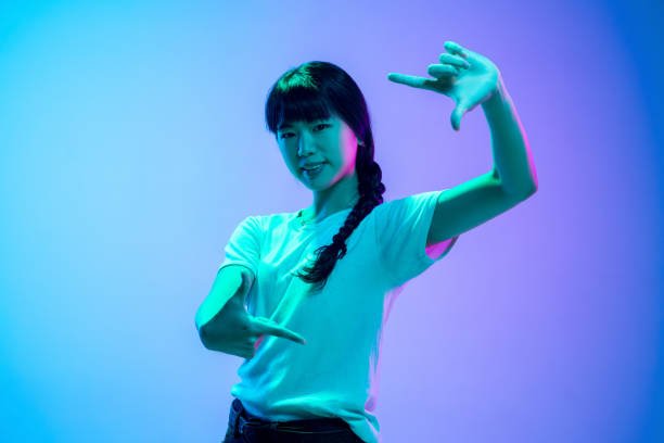 istock Young asian woman's portrait on gradient blue-purple studio background in neon light 1284071062