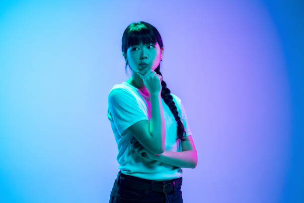 istock Young asian woman's portrait on gradient blue-purple studio background in neon light 1284071069