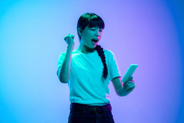istock Young asian woman's portrait on gradient blue-purple studio background in neon light 1284071082