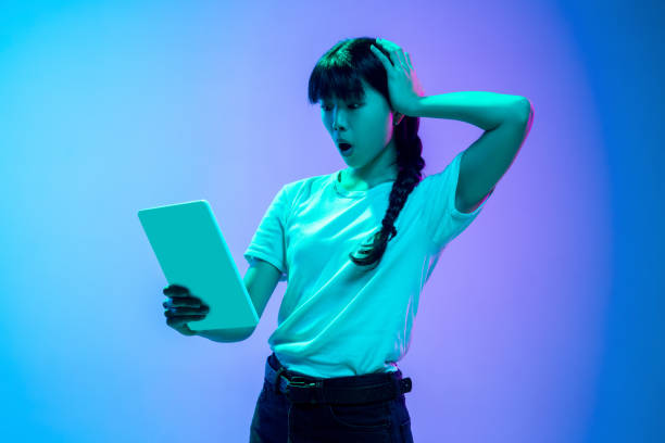 istock Young asian woman's portrait on gradient blue-purple studio background in neon light 1284071084