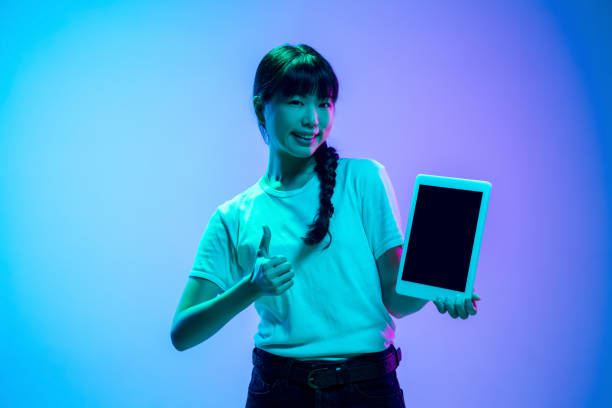 istock Young asian woman's portrait on gradient blue-purple studio background in neon light 1284071087