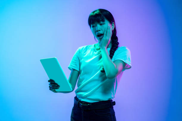 istock Young asian woman's portrait on gradient blue-purple studio background in neon light 1284071090