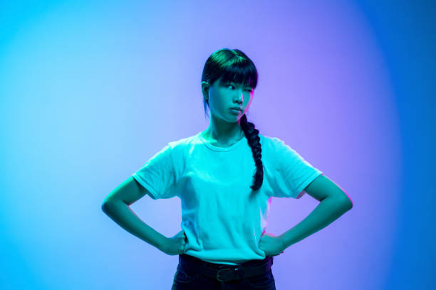 istock Young asian woman's portrait on gradient blue-purple studio background in neon light 1284071093