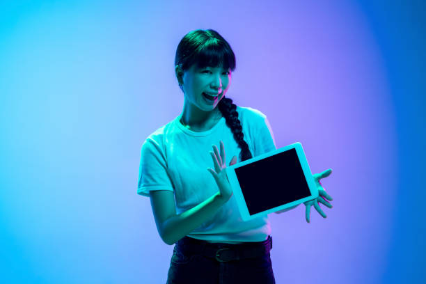 istock Young asian woman's portrait on gradient blue-purple studio background in neon light 1284071095