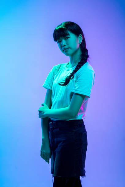 istock Young asian woman's portrait on gradient blue-purple studio background in neon light 1284071101