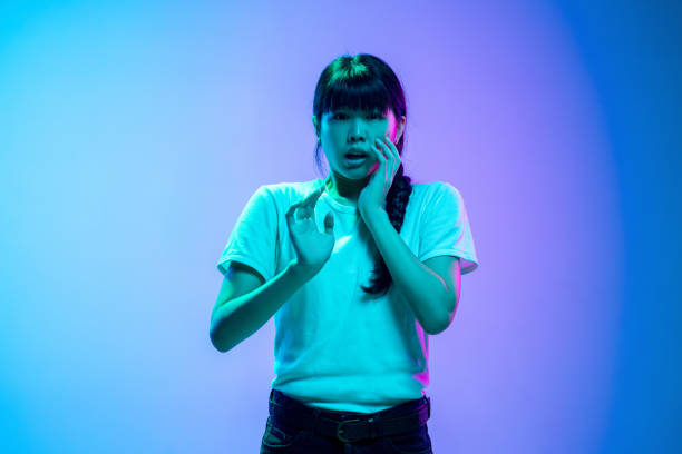 istock Young asian woman's portrait on gradient blue-purple studio background in neon light 1284071102