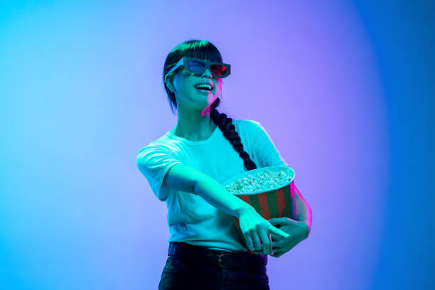 istock Young asian woman's portrait on gradient blue-purple studio background in neon light 1284071103