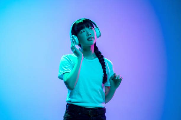 istock Young asian woman's portrait on gradient blue-purple studio background in neon light 1284071116