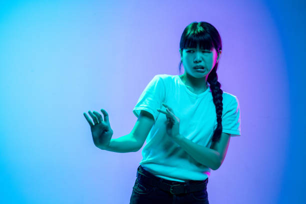 istock Young asian woman's portrait on gradient blue-purple studio background in neon light 1284071123