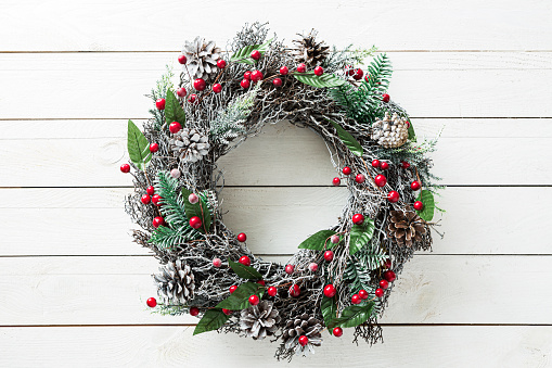 Christmas wreath on white wooden background. Winter holiday - traditional, rustic home decoration. Layout with free copy (text) space.