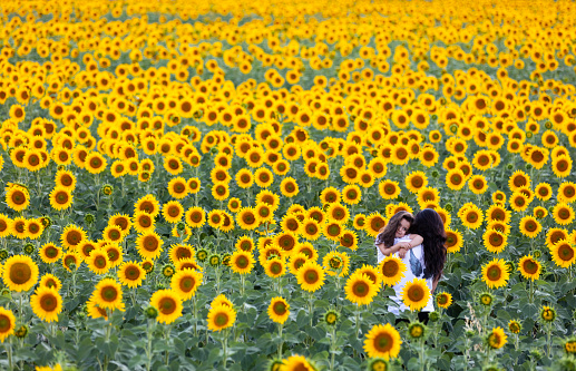 Mother and daughter playing in sunflower field