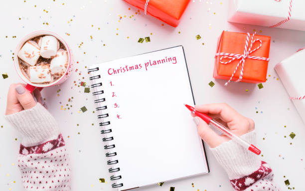 istock Christmas Planning. Woman writing plans for Xmas and drinking cocoa with marshmallows 1284074573