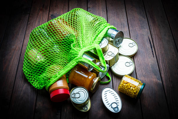Non-perishable foods coming out a green reusable shopping bag. Copy space
