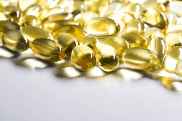 白い背景に黄金の、光沢のあるオイルカプセル。cbdオイルまたはタラ肝油 - fish oil vitamin pill cod liver oil nutritional supplement ストックフォトと画像
