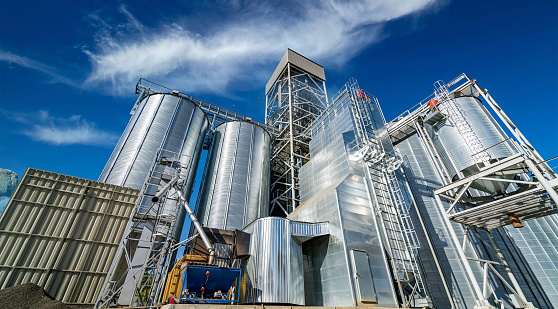 Tanks and agricultural silos of grain elevator storage. Loading facility building exterior. View from below.