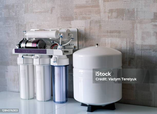 Household Filtration System Water Treatment Concept Use Of Water Filters At Home Glass Of Clean Water And Filters On A Blurred Background Stock Photo - Download Image Now