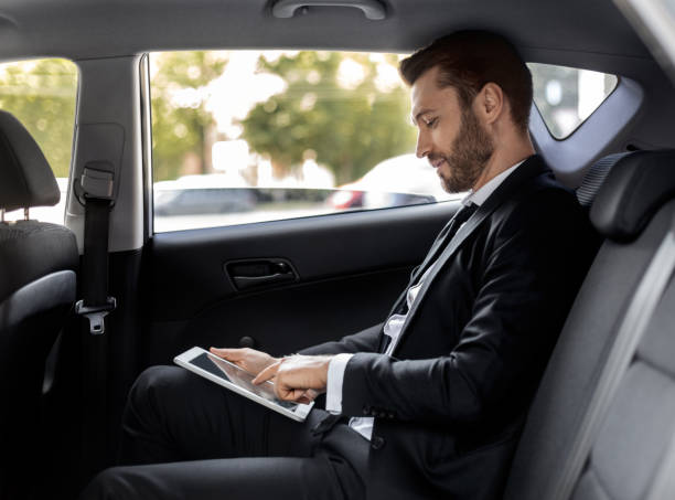 istock Wealthy man working on digital pad while going to airport 1284079193
