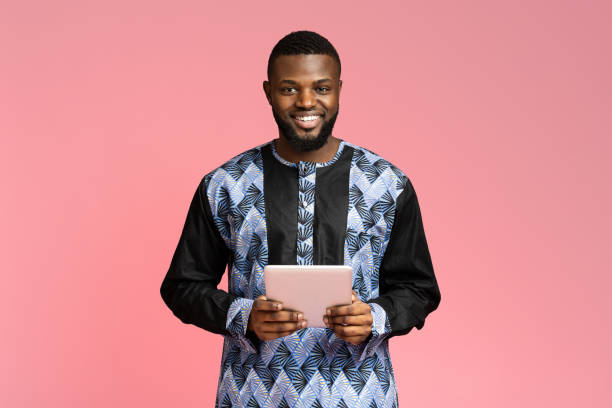 istock Positive black guy using digital tablet, wearing african t-shirt 1284079367