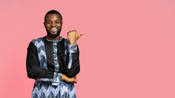 istock Laughing black man in african costume pointing at free space 1284079397