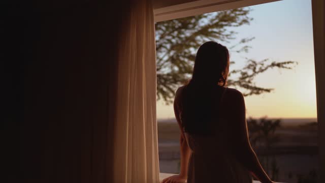 Young woman looking through hotel window