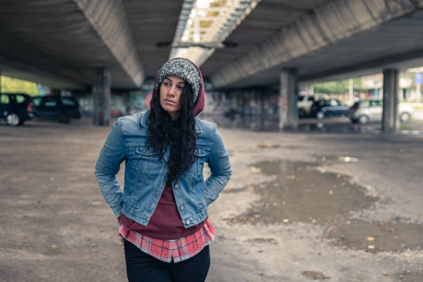 молодая депрессивная бездомная девушка или женщина, стоящая одна под мостом на улице в холодную погоду, чувствуя беспокойство брошенных и � - dirty grunge teenager relationship difficulties стоковые фото и изображения